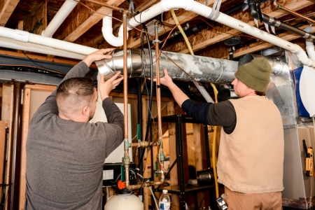 two workers installing vents and ductwork
